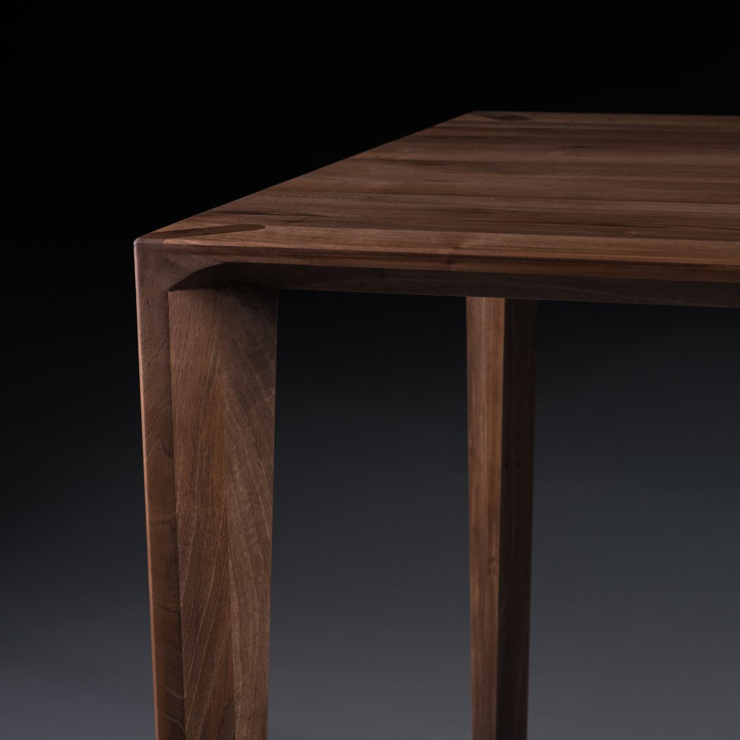 Dark walnut wood table with a smooth finish and sleek, angular design, highlighting rich brown tones and natural grain patterns.