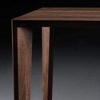 Elegant dark wood table with smooth, natural grain patterns and clean lines against a muted background.