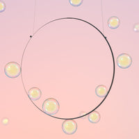 "Minimalist circle design with sparkling, iridescent bubbles against a soft pastel pink background."