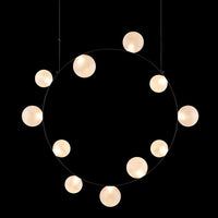 Elegant round pendant light with soft white globes on a sleek black background. Modern, minimalist design.