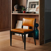 Modern black chair with a sleek design featuring a warm orange leather seat. Perfect for contemporary decor.