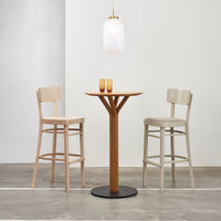 Light wooden bar stools with beige cushions and a sleek, natural wood table against a neutral wall backdrop.