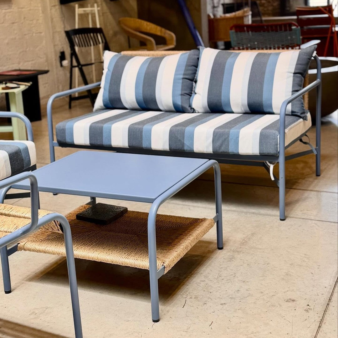 Blue and white striped patio sofa with matching blue side table and woven details. Modern outdoor furniture design.