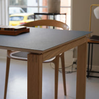 Modern oak table with a sleek dark gray tabletop and minimalist design, featuring clean lines and natural wood grain.
