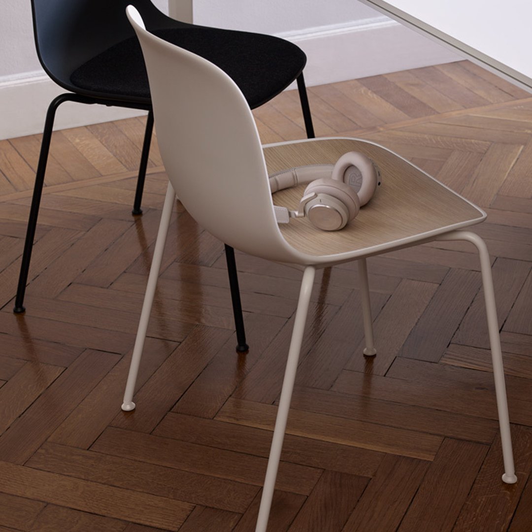"Modern chairs in black and cream with a wooden seat, set against a herringbone wood floor."