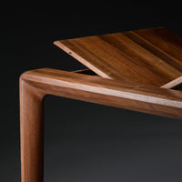 Wooden table with rich brown tones and natural grain patterns, featuring an angular design and a sleek finish.