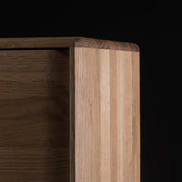 Natural wood cabinet corner with light and dark oak stripes against a black background.