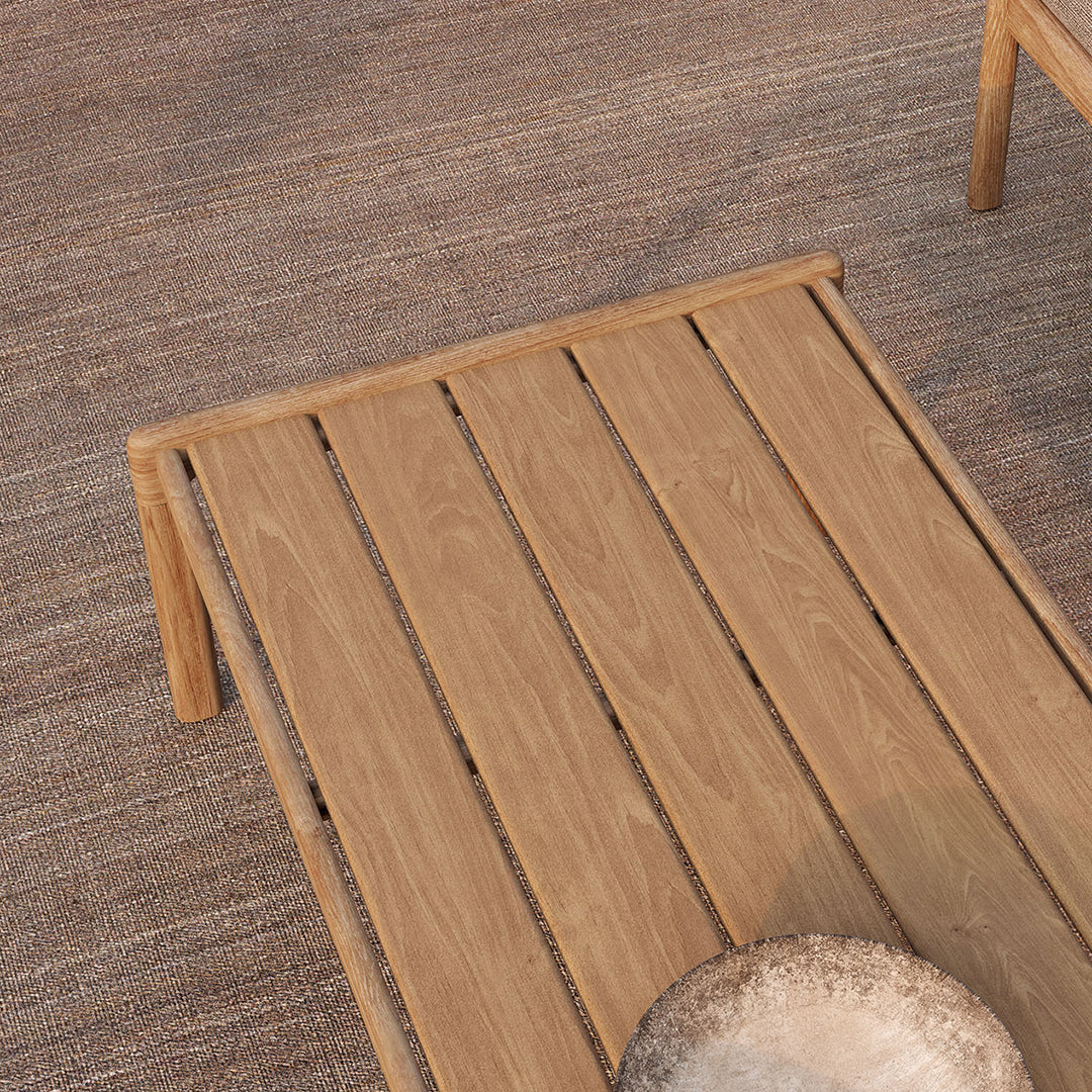 Light wood slatted coffee table, natural finish, on a textured beige rug background. Modern and minimalist design.
