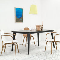 Stylish black dining table with beige and white chairs, accented by a vibrant blue wall art and a soft yellow pendant light.