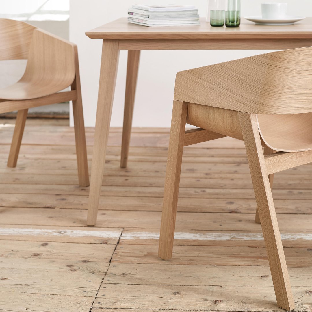 Light wood table and chairs with a natural finish, set against a light wooden floor and minimalist decor.