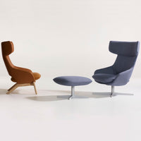 "Brown and gray upholstered chairs with smooth, modern lines and round cushion detailing against a light background."