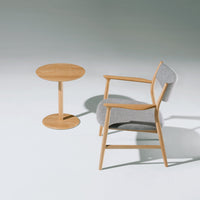 Light wood chair with gray upholstery and matching circular side table, minimalist design, smooth finishes.