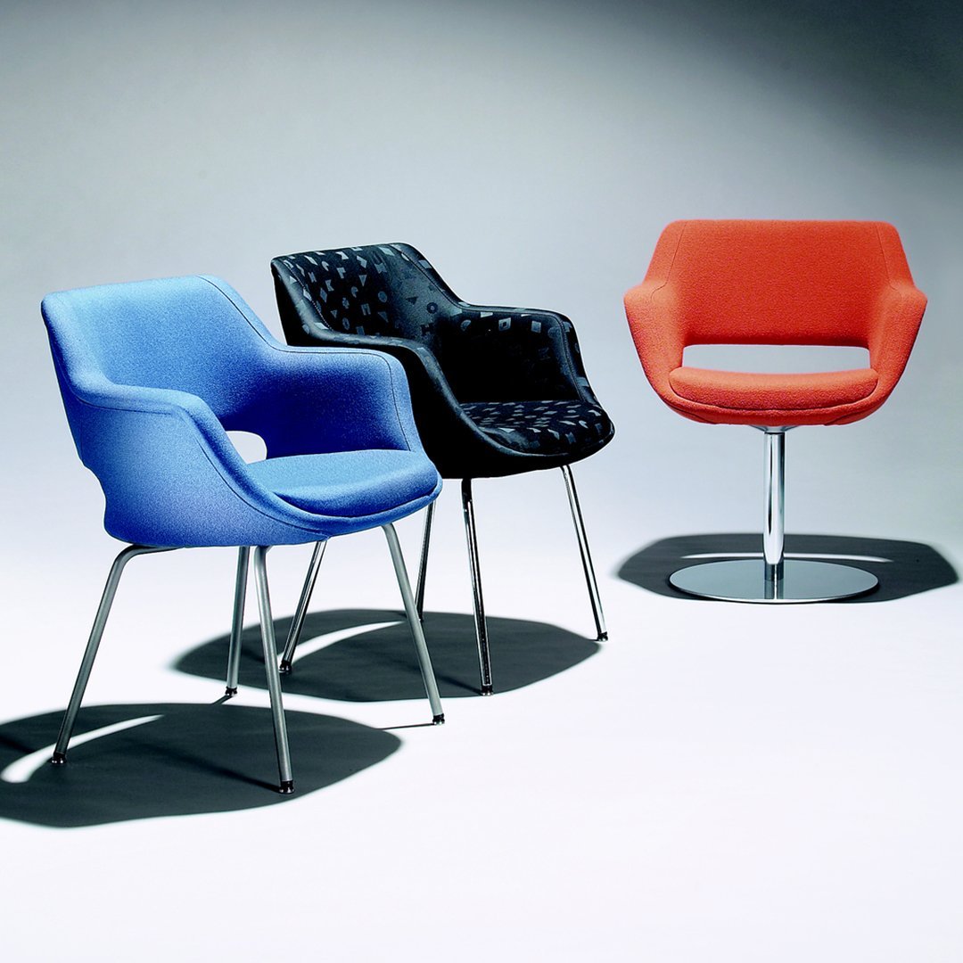 Set of three armchairs in vibrant blue, sleek black, and bold orange with modern patterns and polished metal legs.