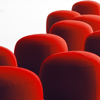 Red upholstered stools in a smooth, rounded design, creating a vibrant and modern seating arrangement.