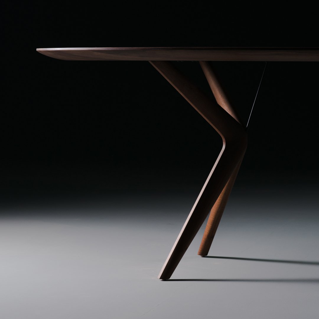 Sleek, dark wood table with a smooth finish and elegant, minimalist design emphasizing geometric lines.