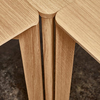 Light oak wood table corners with textured grain pattern and smooth finish, showcasing neutral tones.