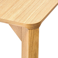 Light oak wood table corner with a smooth, natural grain pattern, showcasing warm, earthy tones.