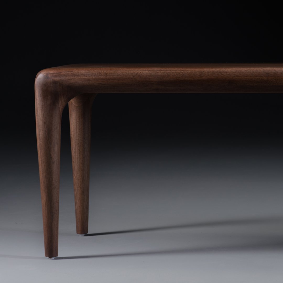 Elegant dark brown wooden table with sleek, tapered legs and a smooth finish against a gradient black to gray background.
