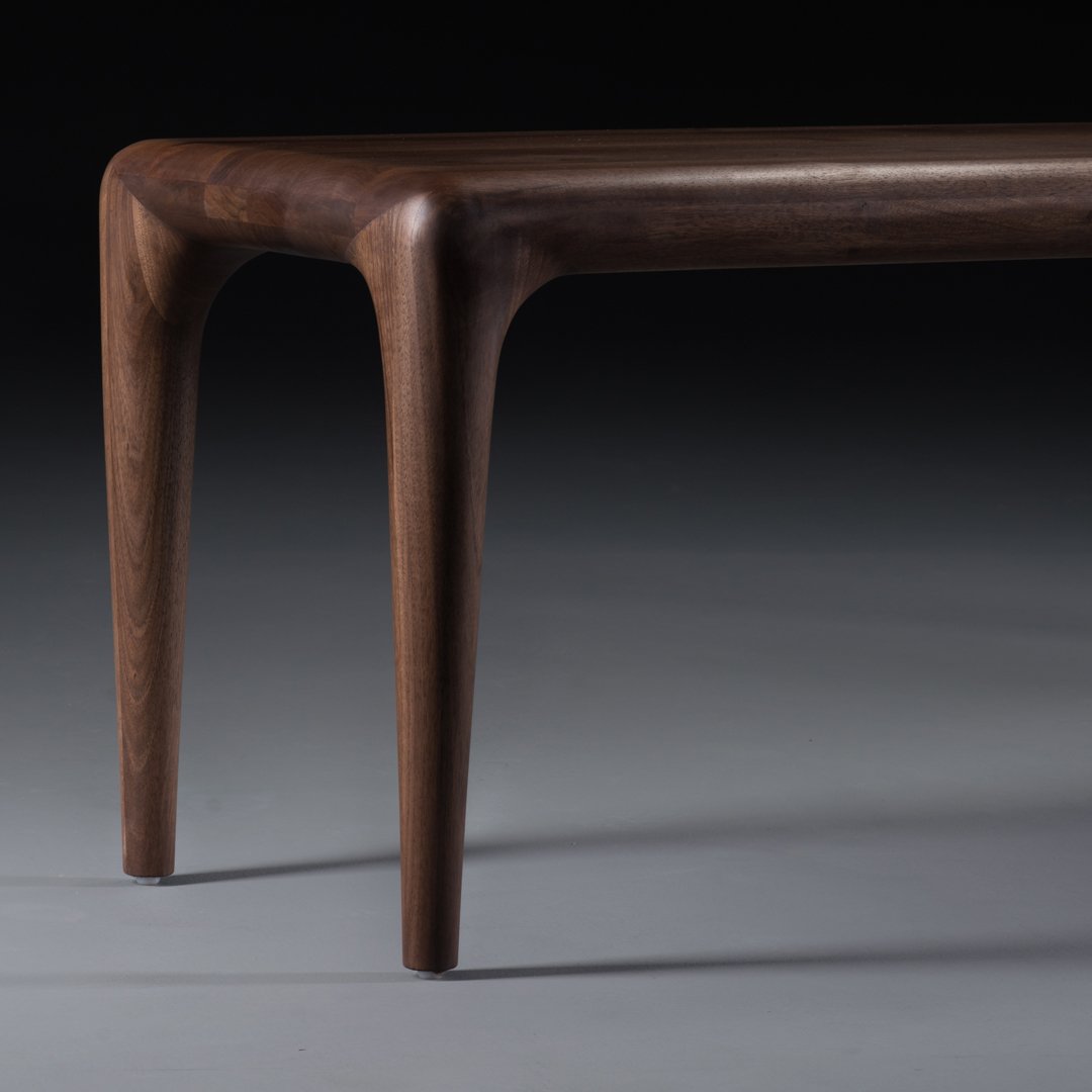 Elegant dark walnut wood coffee table with smooth, curved edges and a rich, natural finish.