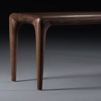 Elegant dark walnut wood coffee table with smooth, curved edges and a rich, natural finish.
