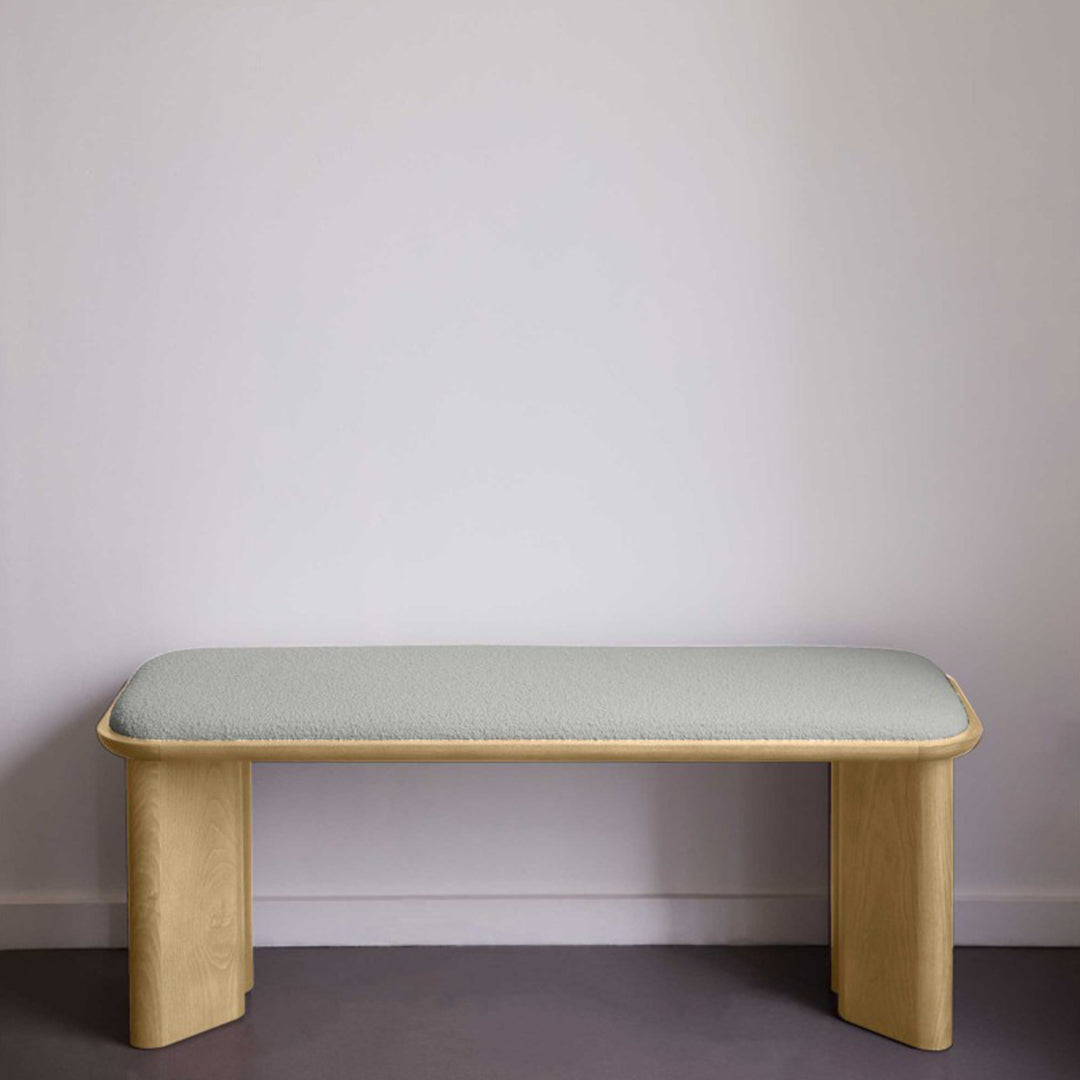 Light wood bench with soft green fabric upholstery, featuring a minimalist design and smooth lines. Perfect for modern interiors.