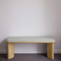 Light wood bench with soft green fabric upholstery, featuring a minimalist design and smooth lines. Perfect for modern interiors.