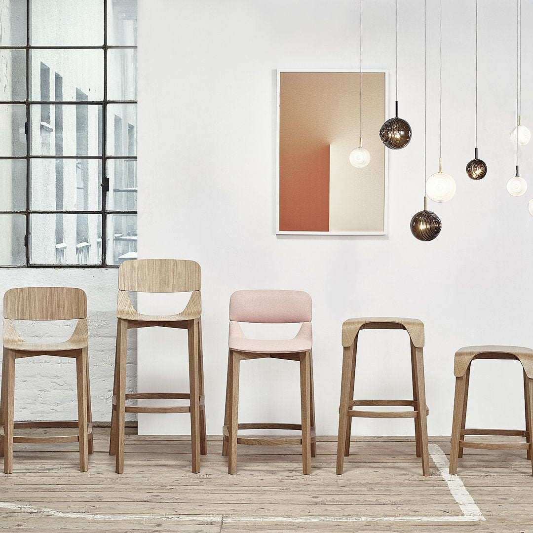 "Modern wooden bar stools in natural wood, soft pink, and white, set against a neutral backdrop with pendant lights."