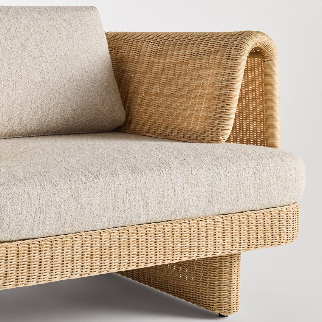Beige fabric cushion on woven rattan sofa with a textured natural finish and curved arm design.