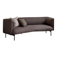 Curved gray sofa with dark cushions and sleek black metal legs, featuring a minimalist and modern design.