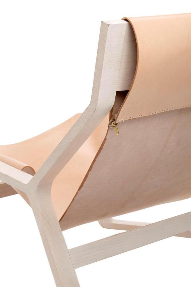 Beige leather lounge chair with smooth, minimalist design and light wooden frame, showcasing clean lines and subtle elegance.