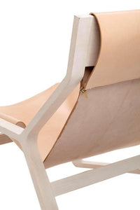Beige leather lounge chair with smooth, minimalist design and light wooden frame, showcasing clean lines and subtle elegance.