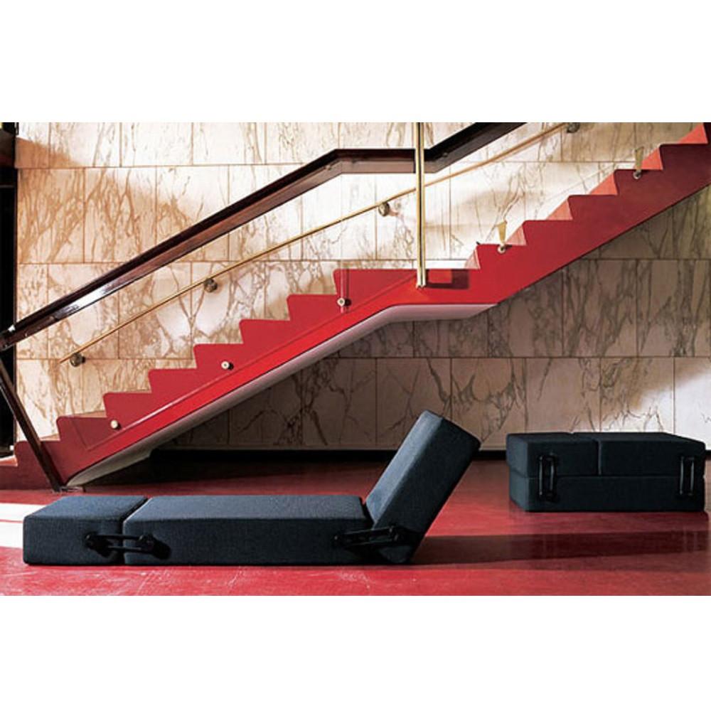 Black foldable lounge chair against bold red and marble patterned backdrop, featuring stylish modern design.