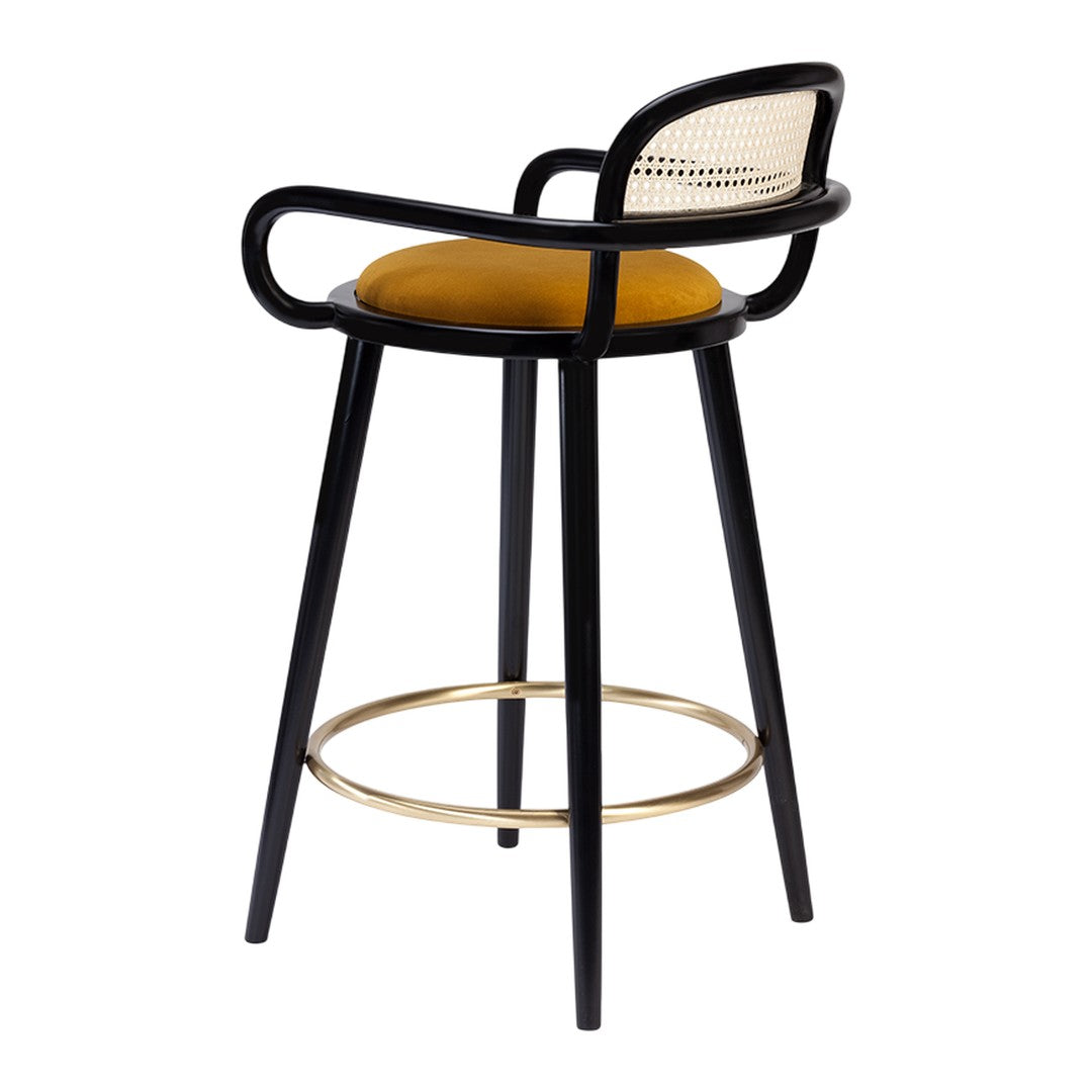 Black wooden bar stool with a gold footrest and mustard yellow upholstered seat, featuring a cane backrest design.