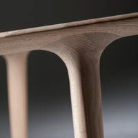 Light natural wood table with smooth, minimalist curves and a soft grain pattern, adding a modern touch to any space.