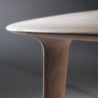 Smooth, light wood table surface with gentle curves and a soft finish against a muted gray background.