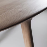 Natural wood table close-up featuring smooth grain and warm beige tones. Elegant, minimalist design with organic shapes.