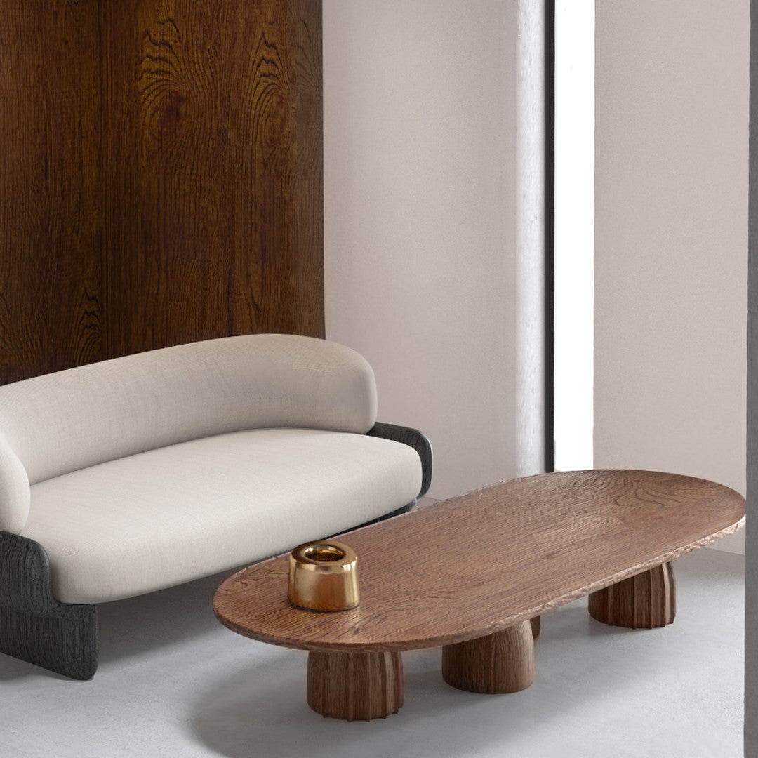 Modern beige and black sofa paired with a rustic brown wooden coffee table, featuring round pedestal legs.