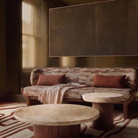 Earthy tones with geometric patterns on a cozy sofa and two round tables, set in a warm, inviting interior.