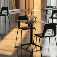 Modern black chairs and a sleek black table on glossy grey tiles, accented by amber and teal glassware.