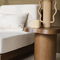 Cream textured upholstery on a cozy sofa with a warm wooden side table and neutral ceramic vase.