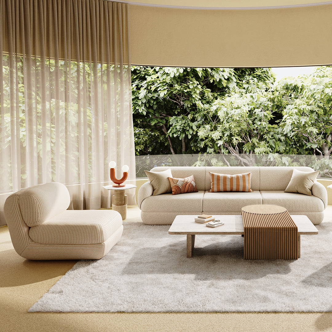 Beige and cream sofa with striped accents, light wooden coffee table, and soft white rug in a sunlit living space.