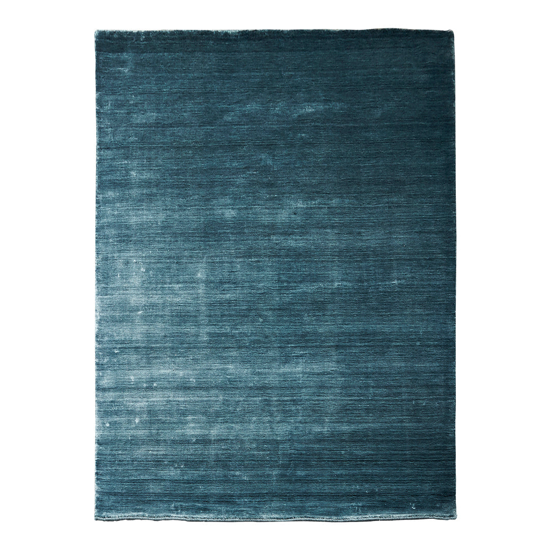 Teal area rug with a textured, gradient pattern, featuring deep blue hues and subtle variations for added depth.