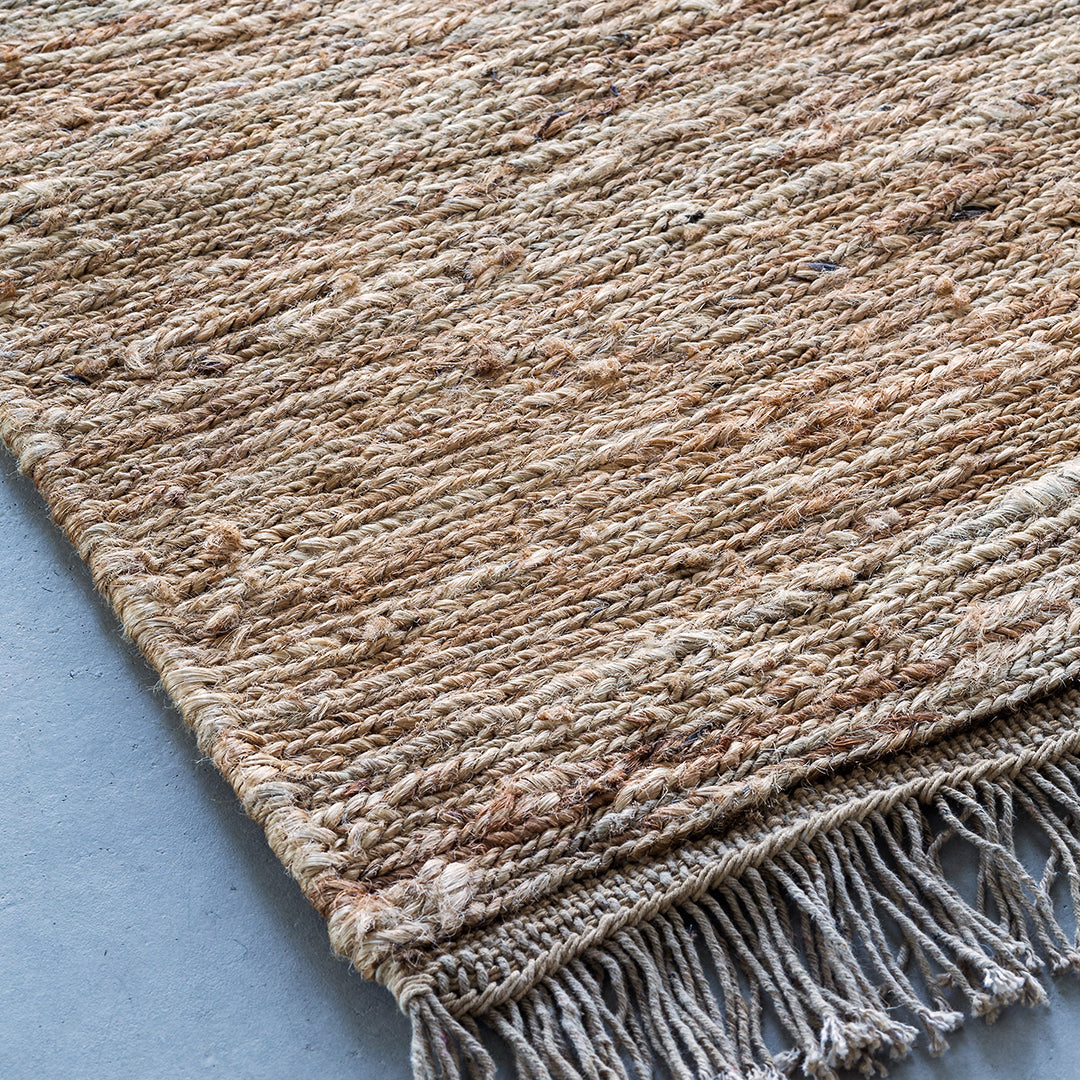 Textured beige rug with subtle earthy tones and fringed edges, perfect for adding warmth to any space.