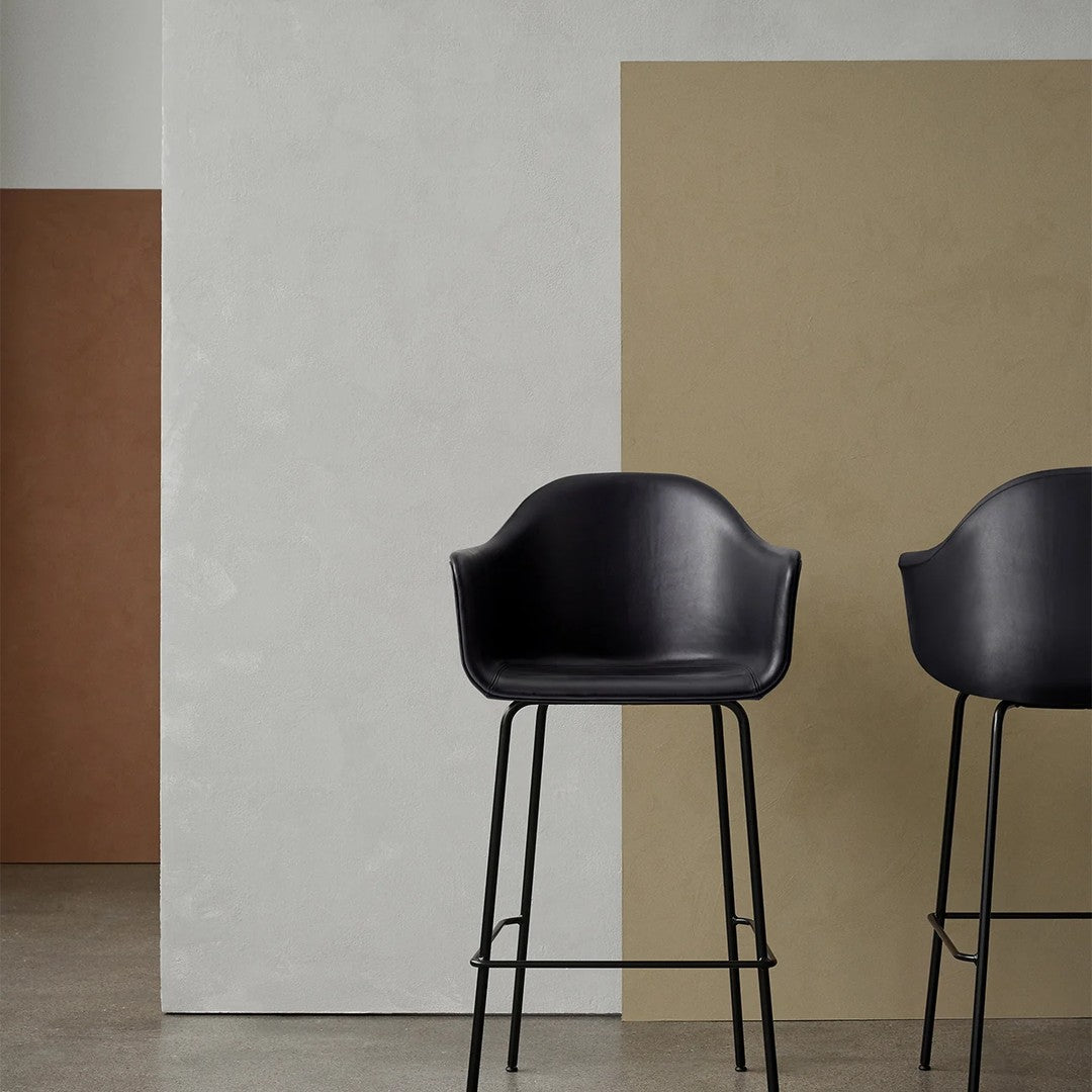 Black bar stools against a minimalist backdrop of beige and terracotta walls, highlighting modern color contrast.