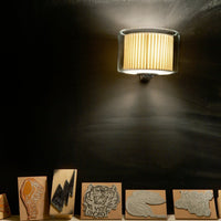 "Backlit lamp illuminates patterned wooden stamps in orange and black on a dark background."