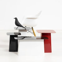Set of modern side tables in glossy black, white, and red finishes with smooth, minimalist designs.