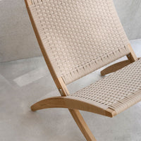Beige woven chair with natural wood frame and a textured pattern, set against a light concrete background.