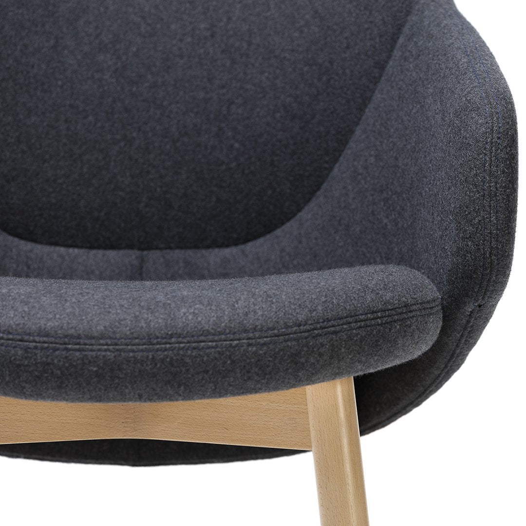 Cozy dark gray upholstered chair with a smooth, rounded design and light wood legs, perfect for modern interiors.