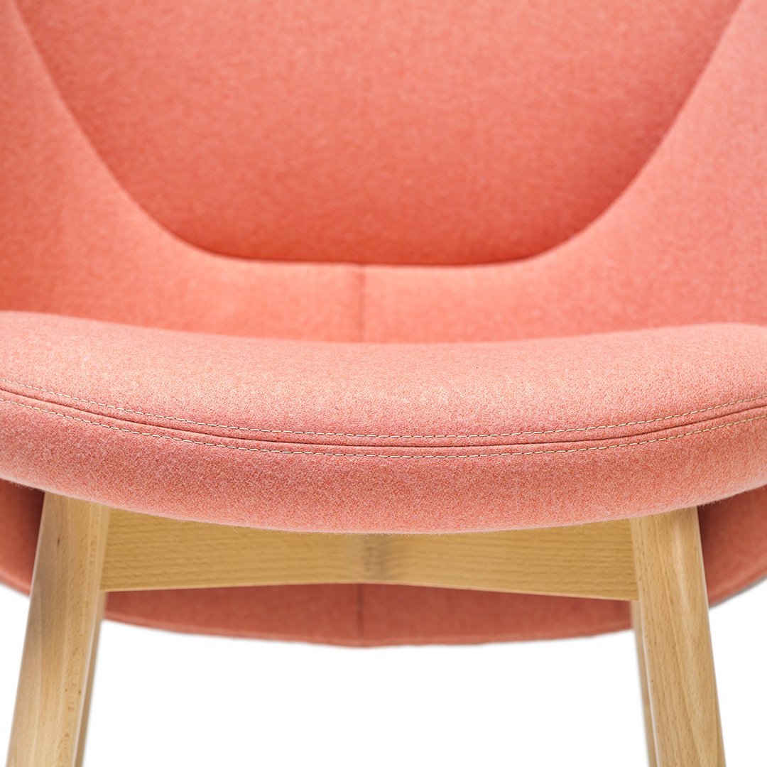 Pink fabric lounge chair with textured upholstery and wooden legs. Modern design, perfect for stylish interiors.