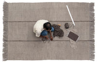 Gray woven rug with subtle stripes and fringed edges, showcasing a minimalist pattern. Perfect for modern decor.